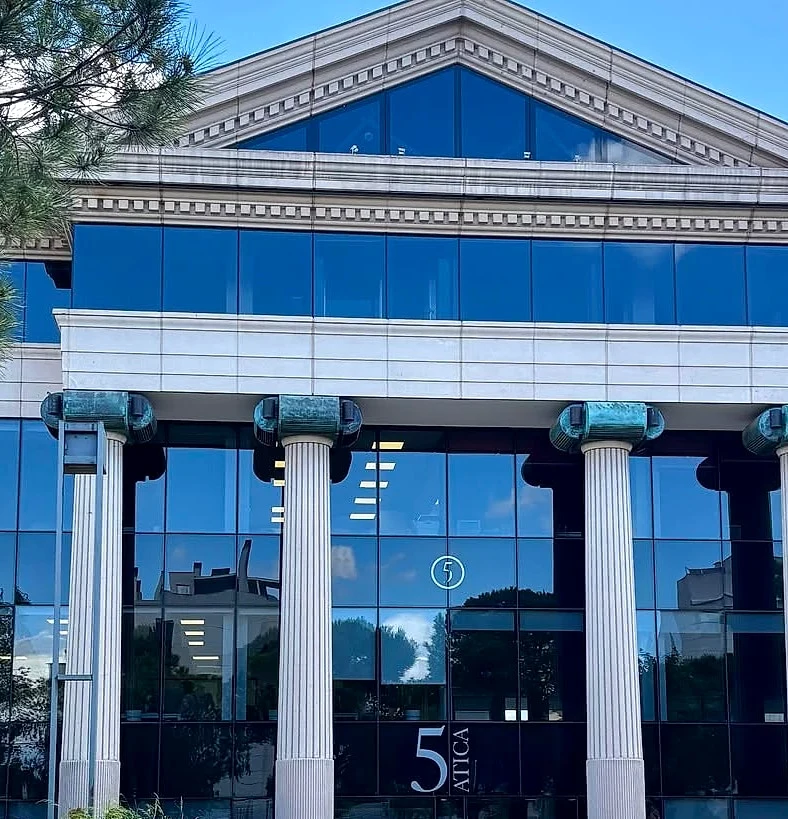 Fachada del Edificio Ática 5, con columnas blancas y el rótulo 5 Ática en la entrada
